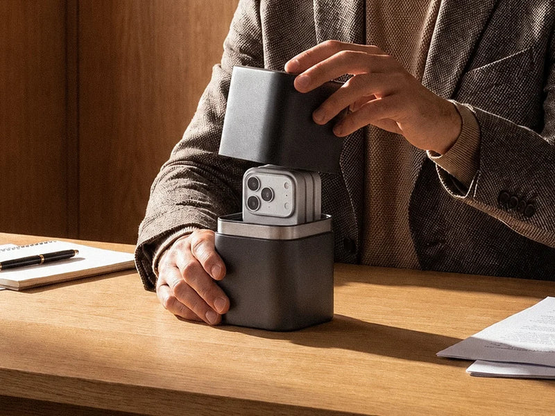Man placing a smartphone into the Velter Faraday capsule on a desk