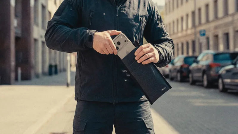 Man putting a smartphone into a Velter Faraday sleeve on the street