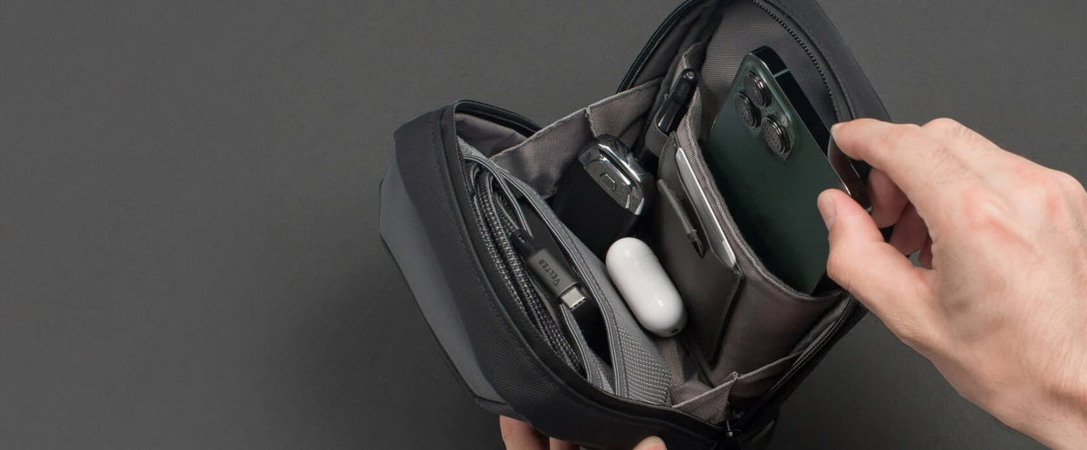 Sling bag organizer with a phone, earbuds, a key fob and a cable